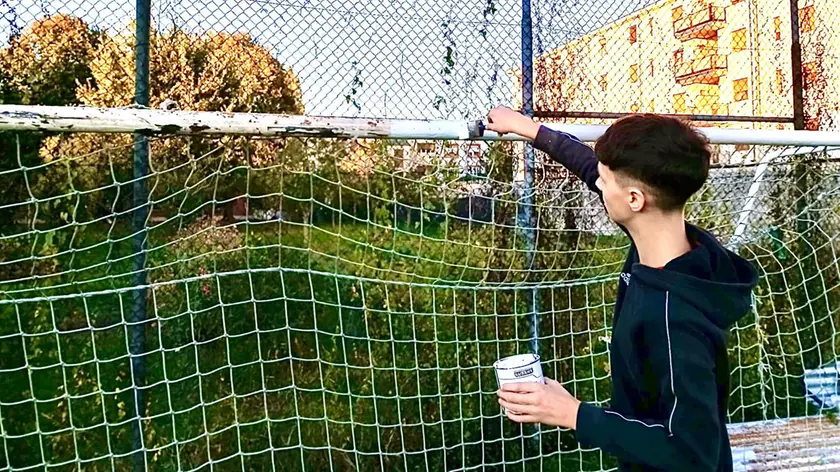 Matteo armato di pennello e pittura per sistemare le porte da calcio