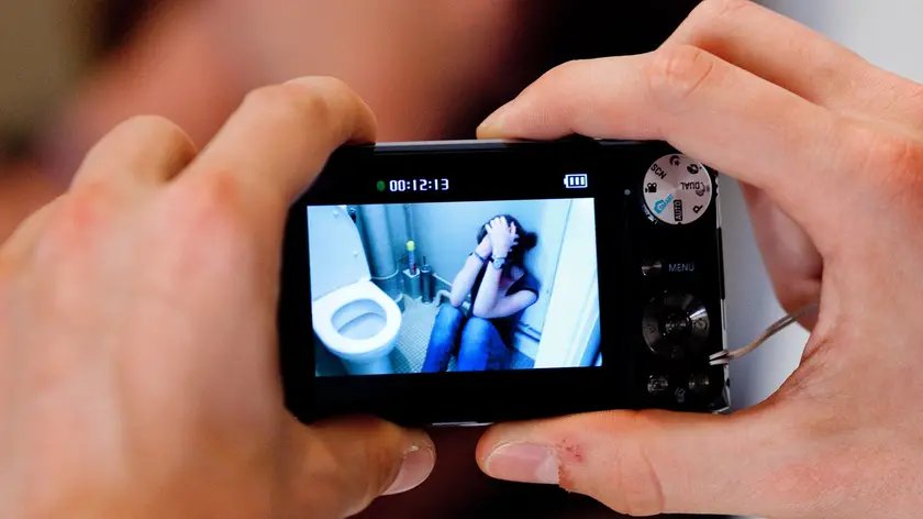 Teenage boy taking picture of a teenage girl at the toilets.