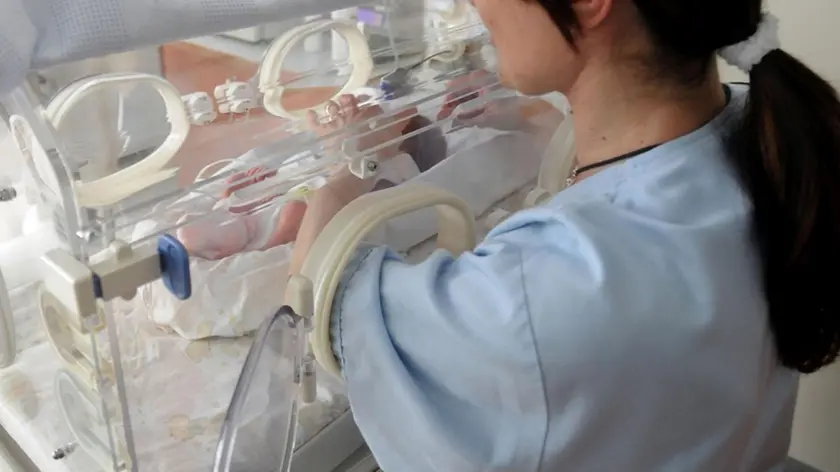 Una infermiera guarda un neonato in ospedale ANSA