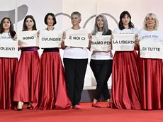 Alcune delle molte partecipanti all’iniziativa contro la violenza verso le donne mostrano il loro messaggio sul red carpet della Mostra del Cinema