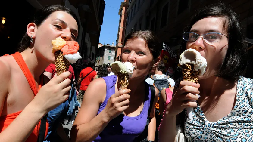 Tre ragazze mangiano del gelato, nel centro storico di Roma. ANSA/CLAUDIO ONORATI