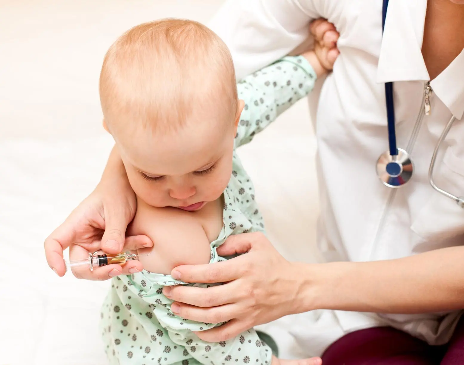 Doctor giving a child an intramuscular injection in arm, shallow DOF