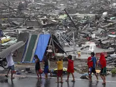 Filipino children carry their belongings during a heavy downpour walk past rubble of housesin the super typhoon devastated city of Tacloban, Leyte province, Philippines 10 November 2013. ANSA/DENNIS M. SABANGAN