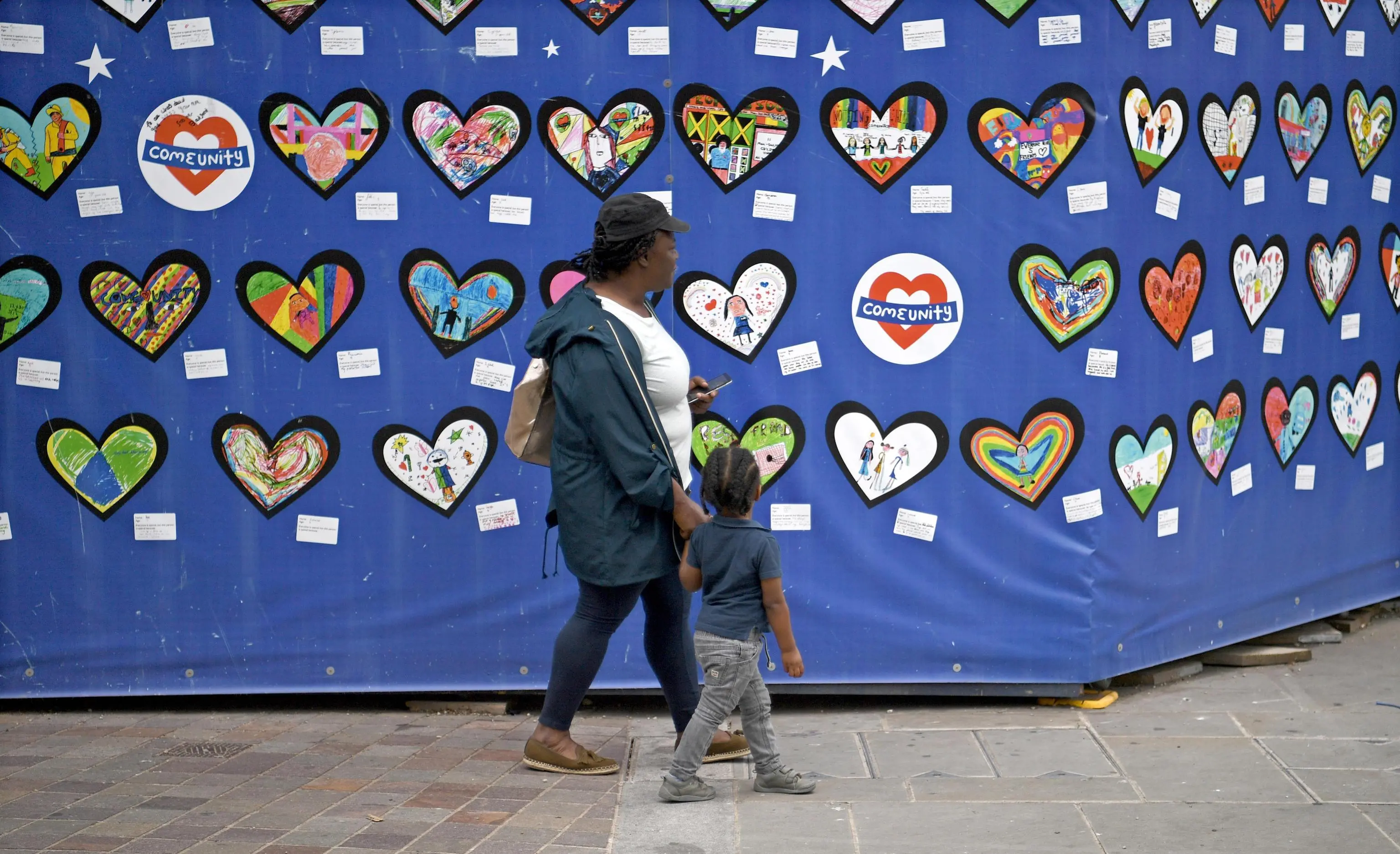 epa06804883 A woman and a child look at tributes for the victims of the Grenfell Tower fire in London, Britain, 13 June 2018, on the eve of the tragedy's first anniversary. The fire hit the 24-storey Grenfell Tower block on 14 June 2017 in North Kensington, West London, killing 72 residents. EPA/NEIL HALL