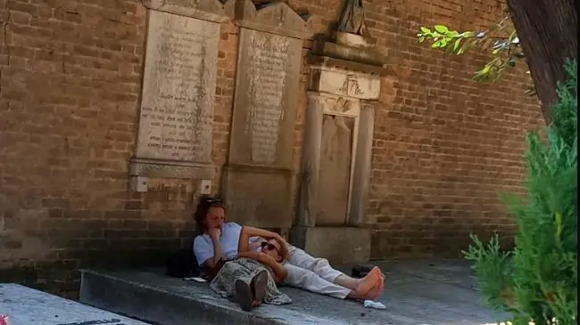 La coppia di giovani che si riposa all'ombra del cimitero