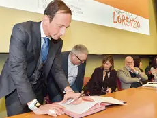 Massimiliano Fedriga firma la Carta di Lorenzo al tavolo dei relatori. Nelle foto piccole il pubblico accorso al convegno dedicato a Parelli Foto Petrussi