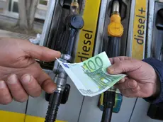 Un benzinaio alla pompa di benzina riceve un biglietto da 100 euro per il pagamento del carburante da un cliente, 12 marzo 2012 a Pisa. ANSA/FRANCO SILVI