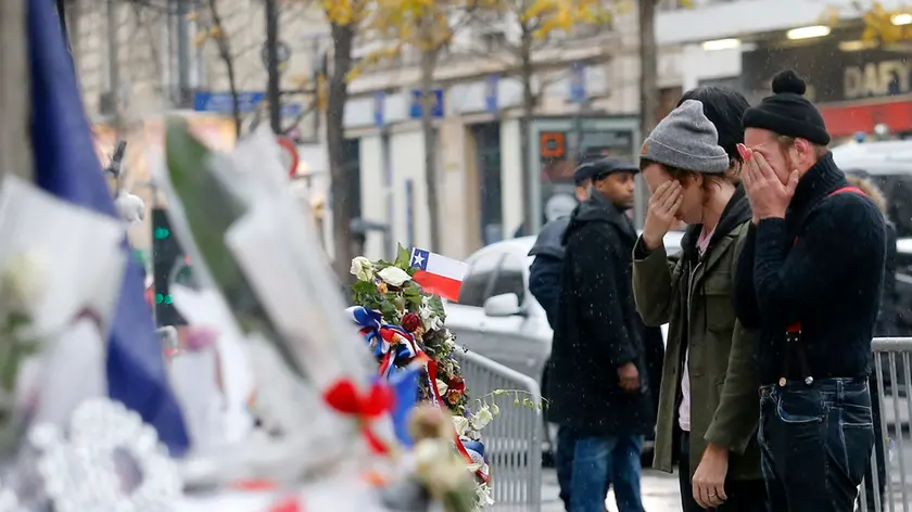 Members of the band Eagles of Death Metal, Jesse Hughes, right, and Julian Dorio pay their respects to 89 victims who died in a Nov. 13 major extremist attack, at the Bataclan concert hall in Paris, France, Tuesday, Dec. 8, 2015. Members of the California rock band Eagles of Death Metal are back at the ravaged Paris theater where they survived a massacre by Islamic extremist suicide bombers. (AP Photo/Jacques Brinon)