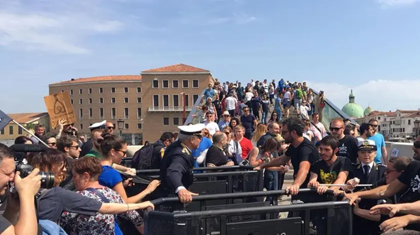 Un gruppo di appartenenti al Centro sociale Morion protesta davanti ad uno dei due varchi, ai piedi del Ponte di Calatrava a piazzale Roma, voluti dal comune per limitare gli ingressi ai turisti a Venezia, 29 aprile 2018. .ANSA