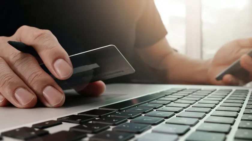 Uomo al computer con carta ricaricabile, truffa truffe sul web