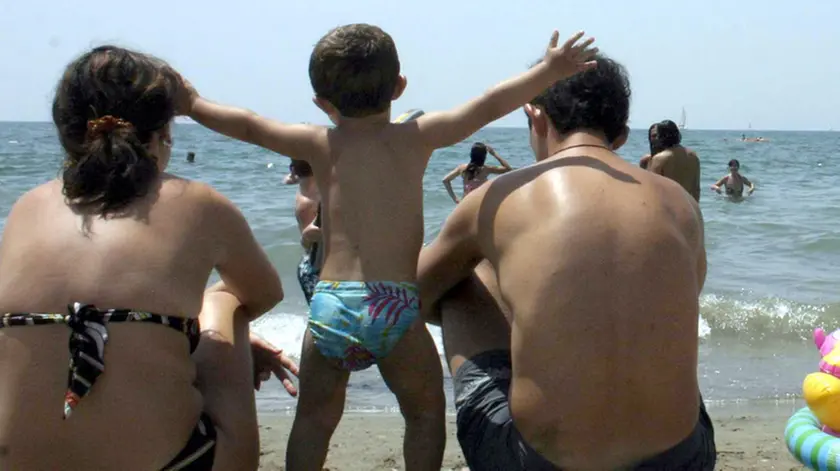 Una famiglia al mare sulla spiaggia in una immagine di archivio.Si chiamerà 'quoziente familiare'' o 'fattore famiglia' ma il governo interverrà per un nuovo fisco a misura di famiglia che tenga conto del numero dei componenti del nucleo familiare. In modo che "famiglie con figli o con situazioni di fragilità possano ricevere un concreto ed indispensabile aiuto in termini di riduzione della pressione fiscale e di accesso agevolato ai servizi". Lo ha ha annunciato oggi 8 novembre 2010 il sottosegretario alla Presidenza del Consiglio Carlo Giovanardi all'apertura della Conferenza nazionale della famiglia. FRANCESCA RUGGIERI / ANSA /