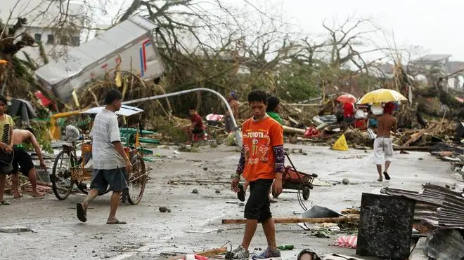 epa03942131 Filipino people walk past a victim left on the side of a street in the typhoon devastated city of Tacloban, Leyte province, Philippines, 09 November 2013. Philippine troops begin to retrieve bodies strewn in areas devastated by Typhoon Haiyan, which was feared to have killed more than 100 people. The most powerful cyclone in three decades battered the Philippines, killing a number of people and displacing over 718,000, disaster relief officials said. Typhoon Haiyan was packing maximum sustained winds of 235 kilometres per hour (kph) and gusts of up to 275 kph as it made five landfalls over the eastern and central provinces of Eastern Samar, Leyte, Cebu and Iloilo, the national weather bureau said. EPA/FRANCIS R. MALASIG