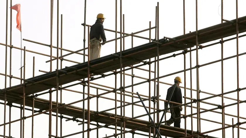 20061101 EDILIZIA SIMBOLO cantiere edile simbolo..epa00853132 Workers are seen atop scaffolding on a building construction site in Beijing, Wednesday 01 November 2006. The growth of China's economy is expected slow down in the fourth quarter to 10 percent, according to the State Information Centre, from 10.4 percent in the third quarter. EPA/MICHAEL REYNOLDS (MICHAEL REYNOLDS/ ) Operai al lavoro in un cantiere edile