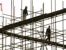 20061101 EDILIZIA SIMBOLO cantiere edile simbolo..epa00853132 Workers are seen atop scaffolding on a building construction site in Beijing, Wednesday 01 November 2006. The growth of China's economy is expected slow down in the fourth quarter to 10 percent, according to the State Information Centre, from 10.4 percent in the third quarter. EPA/MICHAEL REYNOLDS (MICHAEL REYNOLDS/ ) Operai al lavoro in un cantiere edile