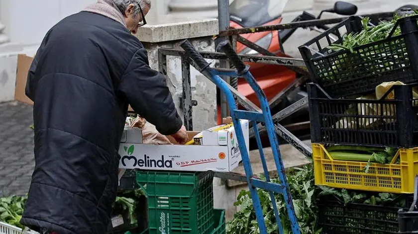 Una donna anziana cerca del cibo tra gli scarti di un mercato, Roma, 20 febbraio 2014. ANSA/ALESSANDRO DI MEO