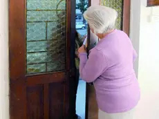 Un anziana che apre la porta a uno sconosciuto