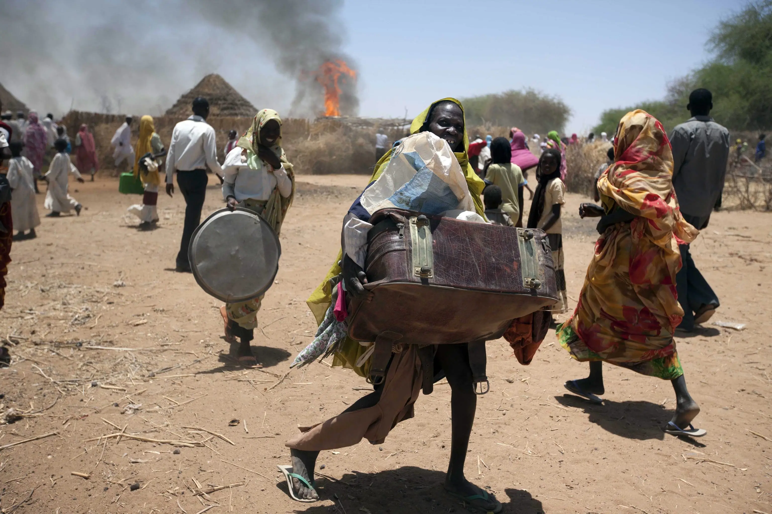 Donne e bambini fuggono da un villaggio cristiano dato alle fiamme in Sudan, dove la guerra è spietata