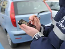 Un'ausiliaria del traffico controlla una vettura parcheggiata entro strisce blu a Pontedera, in un'immagine d'archivio. ANSA/FRANCO SILVI