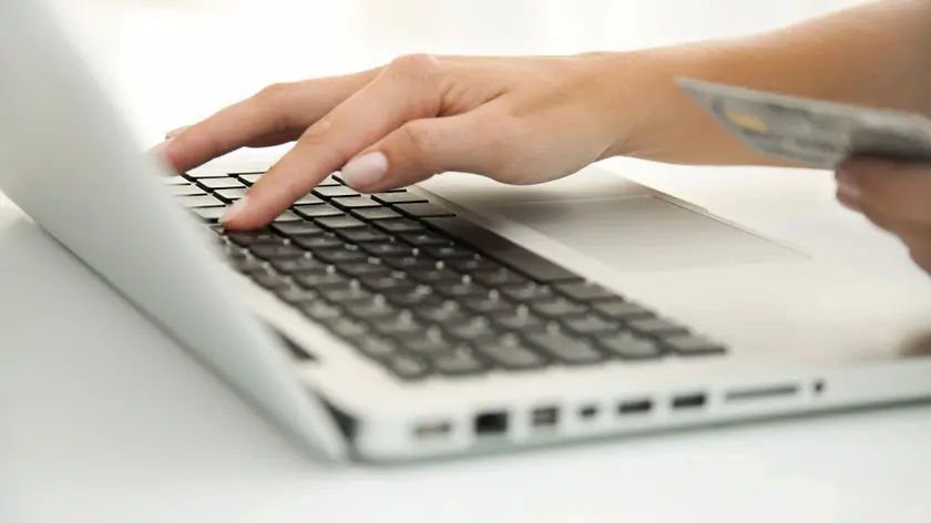 Woman using laptop computer to make an internet purchase, cropped