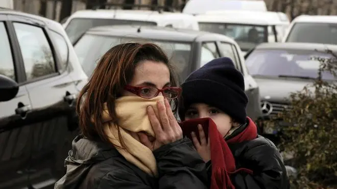 Una madre e il figlio si coprono il viso per proteggersi dallo smog nel centro di Milano, in una foto del 28 gennaio 2010. DANIEL DAL ZENNARO / ANSA