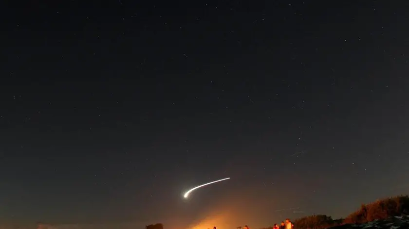 Giovani in spiaggia a Fregene nella notte di San Lorenzo attendono le stelle cadenti, in una immagine dell'11 agosto 2008. Doppio spettacolo celeste nelle notti delle stelle cadenti: la pioggia luminosa di meteore, che quest'anno si annuncia fittissima e straordinaria per la sua visibilita', sara' preceduta al tramonto da un fenomeno insolito: tre pianeti uno accanto all'altro, apparentemente vicinissimi, a formare un piccolo triangolo all'orizzonte. Lo sciame di meteore chiamato anche 'Lacrime di San Lorenzo' perche' si infrange nell'atmosfera della Terra in concomitanza con l'anniversario della morte del santo (che cade il 10 agosto) in realta' e' visibile gia' da questa sera e per i prossimi 6-7 giorni ma il picco di intensita' e' previsto il 13 agosto, poco prima dell'alba, quando si potrebbero contare diverse decine di stelle cadenti all'ora, forse anche un centinaio, di luminosita' media e piu' brillanti. ANSA/ALESSANDRO DI MEO