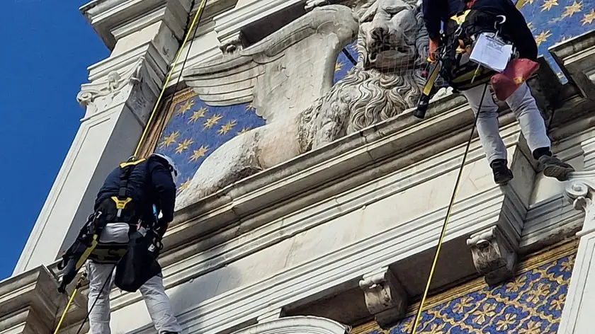 L'intervento dei restauratori specializzati con la fune sulla Torre dell'Orologio (foto Interpress)