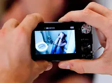 Teenage boy taking picture of a teenage girl at the toilets.