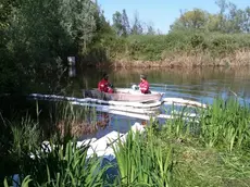 I volontari cercano di arginare l'inquinamento in uno dei laghi dell'oasi stendendo delle panne di contenimento