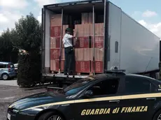 Finanzieri davanti al Tir con nove tonnellate di sigarette di contrabbando, del valore di oltre un milione di euro, scoperto dalla Guardia di finanza a Teano (Caserta), in un'area di servizio dell'autostrada Roma-Napoli, 1 agosto 2014. ANSA / US GDF NAPOLI ++NO SALES EDITORIAL USE ONLY++