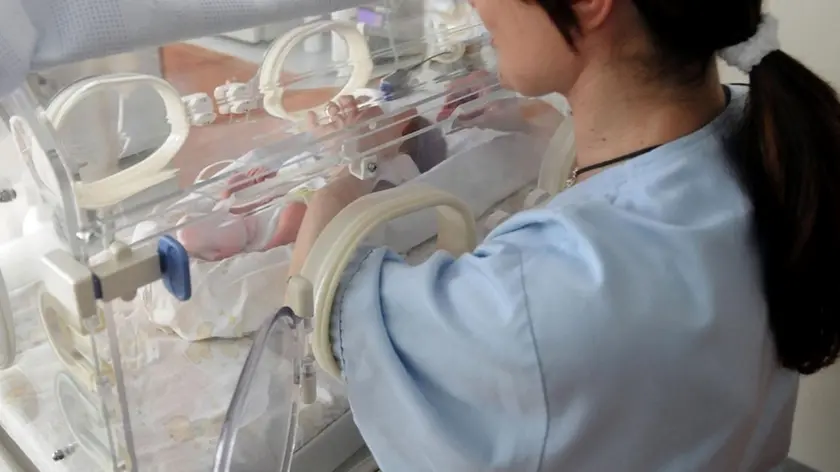 Una infermiera guarda un neonato in ospedale ANSA