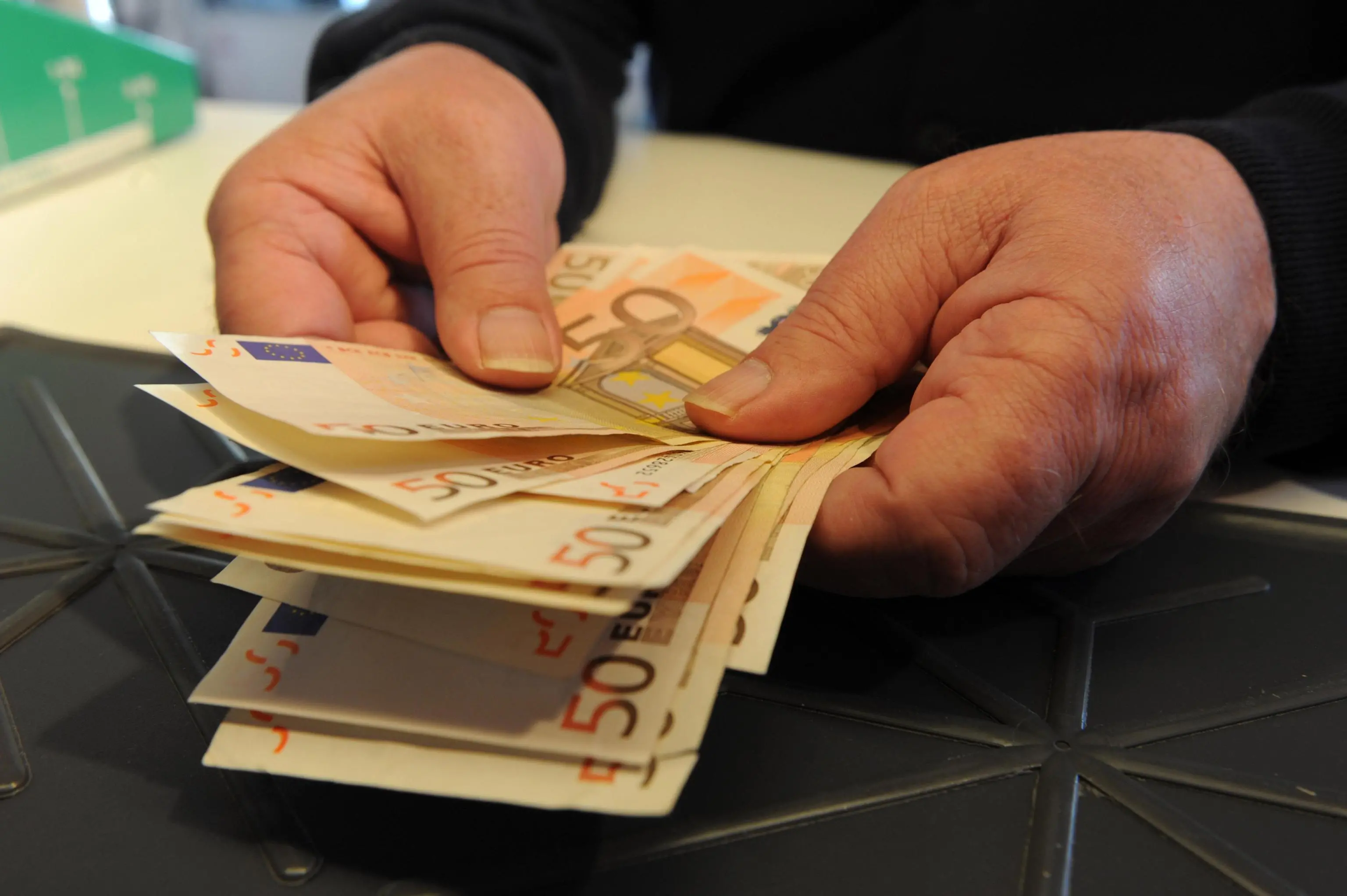 Una persona conta alcune banconote in una banca, Pisa, 15 maggio 2012. ANSA / FRANCO SILVI