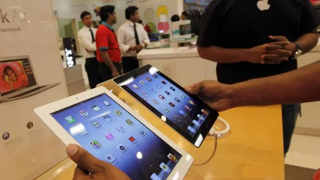 A prospective buyer compares the new iPad tablet computer, left, with the older version at a store in Bangalore, Friday, April 27, 2012. Sales of Apple's new iPad began Friday in the country. (AP Photo/ Rajanish Kakade)