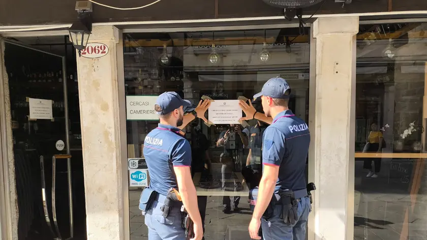 Gli agenti di polizia dopo aver consegnato il provvedimento di chiusura del bar