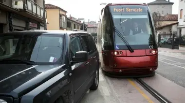 A sinistra il tram bloccato da un suv in via Ca’ Rossa Sopra il marciapiede rotto alla fine di via Cappuccina vicino alla fermata di via Sernaglia. Sotto ancora auto che transitano sui binari e alcuni cittadini che commentano il prossimo avvio del servizio tram Domenica l’inaugurazione, lunedì l’avvio