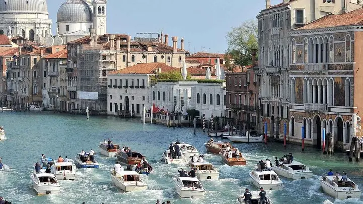 The boat carrying George Clooney and his wife Amal Alamuddin, is surrounded by media and security boats as they cruise the Grand Canal after leaving the Aman luxury Hotel in Venice, Italy, Sunday, Sept. 28, 2014. George Clooney married human rights lawyer Amal Alamuddin Saturday, the actor's representative said, out of sight of pursuing paparazzi and adoring crowds. (AP Photo/Luigi Costantini)