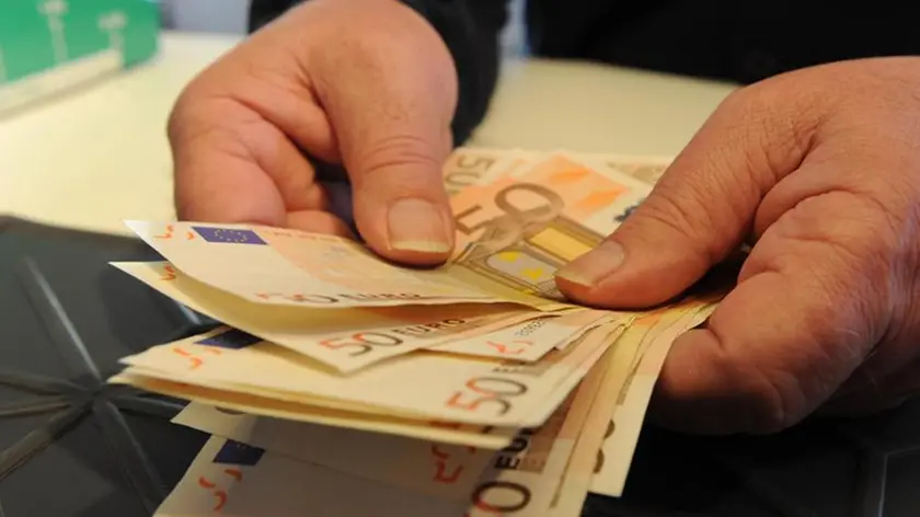 Una persona conta alcune banconote in una banca, Pisa, 15 maggio 2012. ANSA / FRANCO SILVI