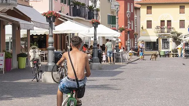 Un ciclista a torso nudo e (più sotto) una donna in costume, fotografati in centro a Caorle (FOTO VIANELLO)