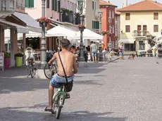 Un ciclista a torso nudo e (più sotto) una donna in costume, fotografati in centro a Caorle (FOTO VIANELLO)